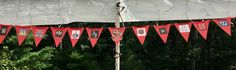 red and white banners hanging from the side of a tent with trees in the background