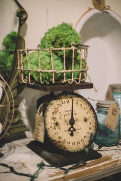 an old clock with moss on it sitting on top of a table next to other items