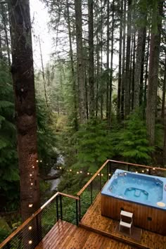 a hot tub sitting on top of a wooden deck next to a lush green forest