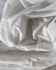 an unmade bed with white sheets and pillows