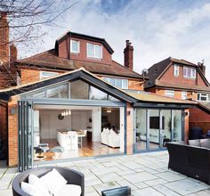 an open living room and dining area in front of a large brick building with lots of windows