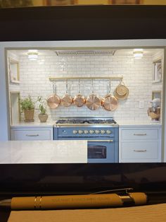 a tv screen showing a kitchen with pots and pans on the stove, next to a pen