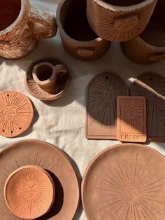 several clay bowls and plates sitting on top of a white tablecloth with sunburst designs