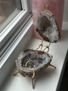 two pieces of jewelry sitting on top of a window sill next to a window