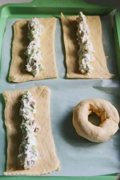 four doughnuts with different toppings on them sitting on a baking sheet next to a bagel