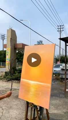 an easel with a painting on it in front of some power lines and buildings