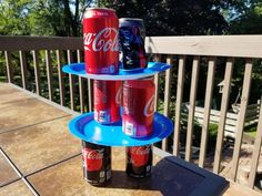 three soda cans stacked on top of each other in front of a wooden deck railing