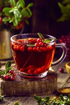 a cup filled with red berries sitting on top of a wooden table