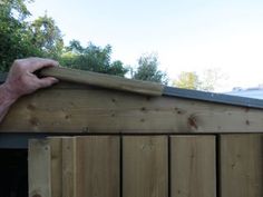 a man is holding onto the side of a wooden fence with his hand on it