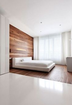 a white bed sitting in the middle of a bedroom next to a wall mounted tv