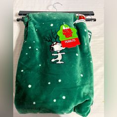 a green blanket with a snoopy christmas tree on it, hanging from a clothes rack