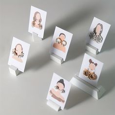 five different types of earrings on display with white cards and magnets attached to them