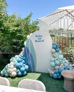 a baby board sign surrounded by blue and white balloons in the shape of a surfboard