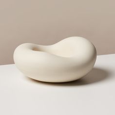 a white sculpture sitting on top of a table next to a wall in the background