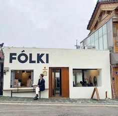 a man standing outside of a store next to a building with a sign that says folki