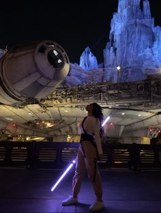 a woman standing in front of a giant star wars ship at night with lights on