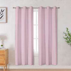 a pink curtain hanging on the side of a window next to a wooden dresser and potted plant