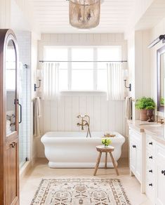 a bathroom with a tub, sink and mirror in it's center area is shown