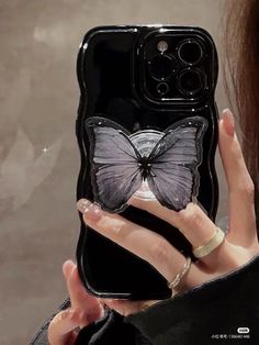 a woman holding up a phone case with a butterfly on it