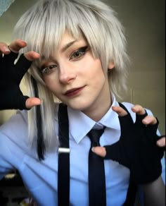 a woman with white hair and black suspenders is wearing a tie, holding her hands behind her head