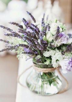 a vase filled with purple and white flowers on top of a table next to a napkin