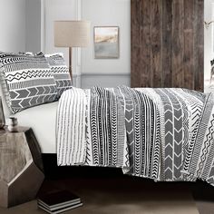 a bed with black and white comforter in a bedroom next to a wooden headboard