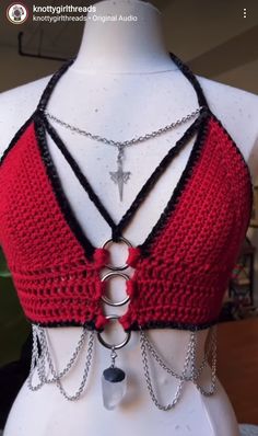 a white mannequin wearing a red and black top with chains attached to it