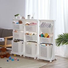 three white storage baskets are stacked on top of each other in front of a couch