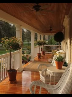 a porch with wicker chairs and potted plants on the front porch, surrounded by wood flooring