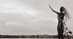 there is a statue on the beach by the water with it's arms in the air