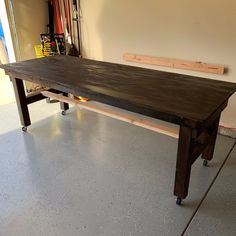 a wooden table sitting in the middle of a room next to a wall with tools on it