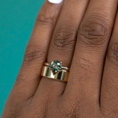 a woman's hand with a ring on it and a green stone in the middle