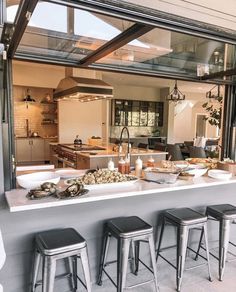 a kitchen filled with lots of counter top space and stools next to an open window