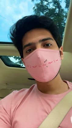 a man wearing a pink face mask with writing on it