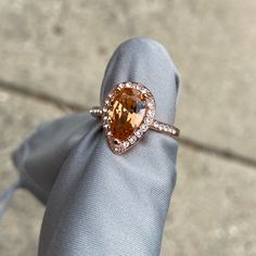 a fancy ring with an orange topaz surrounded by white diamonds on a gray cloth