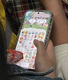 a person holding an iphone with stickers on the screen and their hand is pointing at it