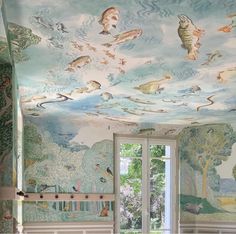 a bedroom decorated with fish and clouds painted on the ceiling, along with large windows