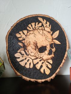 a wooden plate with a skull and leaves on it