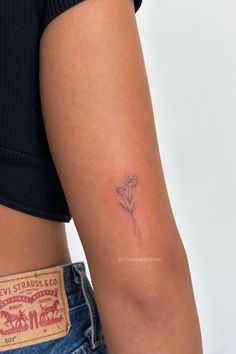 a woman's arm with a small flower tattoo on the left side of her body