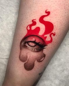 a woman's leg with red ink on it and an eye painted in the shape of a demon