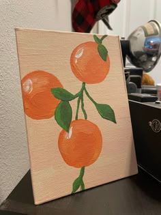 an orange painting is sitting on a table next to a laptop computer and other items