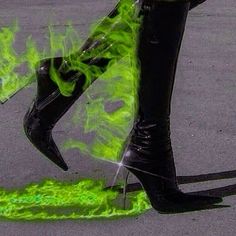 a woman's legs with green paint on them and black high heeled boots