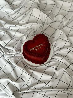 a red heart shaped cake sitting on top of a white table cloth covered in black lines