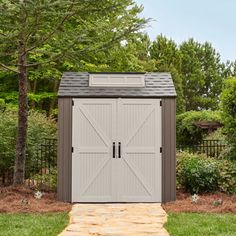 an outdoor storage shed in the middle of a yard with grass and trees around it