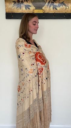 Here is a beautiful antique silk embroidered Manton de Manila shawl dating to the early part of the 20th century circa 1900 to 1910. The silk ground is in a rare buttermilk colour, I think that the listing photos which shows it worn by our model give a good indication of the actual colour. The richly coloured embroidery is in colours including orange, blue, lilac and white and it has long fringing and a hand knotted deep border to each side. The design includes large peony flowers and smaller fl Traditional Cream Dupatta With Floral Print, Cream Silk Dupatta With Floral Embroidery, Embroidered Silk Shawl Scarf, Bohemian Cream Dupatta With Traditional Drape, Vintage Cream Silk Scarf, Vintage Shawl With Traditional Drape For Wedding, Silk Floral Print Shawl, Traditional Cream Silk Shawl, Vintage Wedding Shawl With Traditional Drape