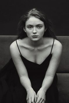 a black and white photo of a woman sitting on a couch with her hands in her lap