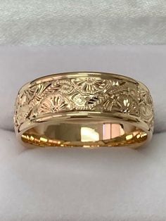 a gold wedding band that has been engraved with flowers and leaves on the inside of it