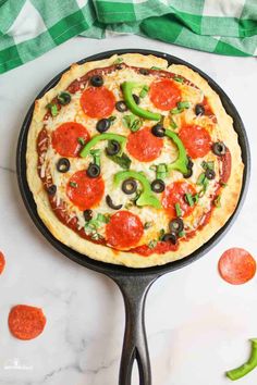 a pizza sitting on top of a pan covered in cheese and pepperoni next to green peppers