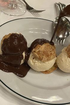 three desserts on a plate with chocolate sauce and ice cream in between them, sitting on a table