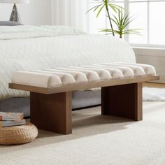 a wooden bench sitting on top of a white carpeted floor next to a bed